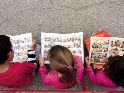 Un nen i dues nenes llegeixen còmics.