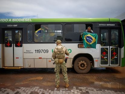 Un partidario de Jair Bolsonaro sostiene una bandera al llegar en autobús a la Academia Nacional de la Policía Federal en Brasilia