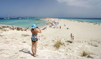 Una mujer fotografía la playa de Ses Illetes, en Formentera (Islas Baleares).
