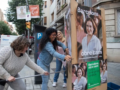 Tres mujeres pegan carteles en el barrio barcelonés del Guinardó de la candidata a la alcaldía por Barcelona en Comú, Ada Colau, este domingo.