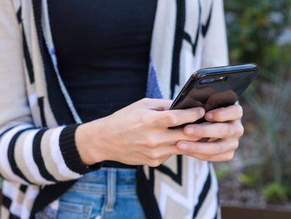 Una mujer envía un mensaje de texto con su teléfono móvil.