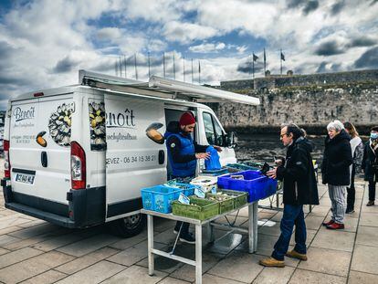 Vecinos de Concarneau compran marisco a un vendedor ambulante ante esta ciudad bretona con altos índices de satisfacción de vida.