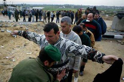 Un policía palestino registra a un trabajador ayer en el paso fronterizo de Erez.