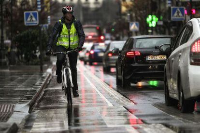La lluvia no es una excusa para este joven que circula en bici por el carril de la calle Mayor con una mountain bike