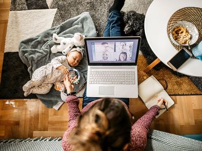 Una madre trabaja en casa con su bebé al lado.