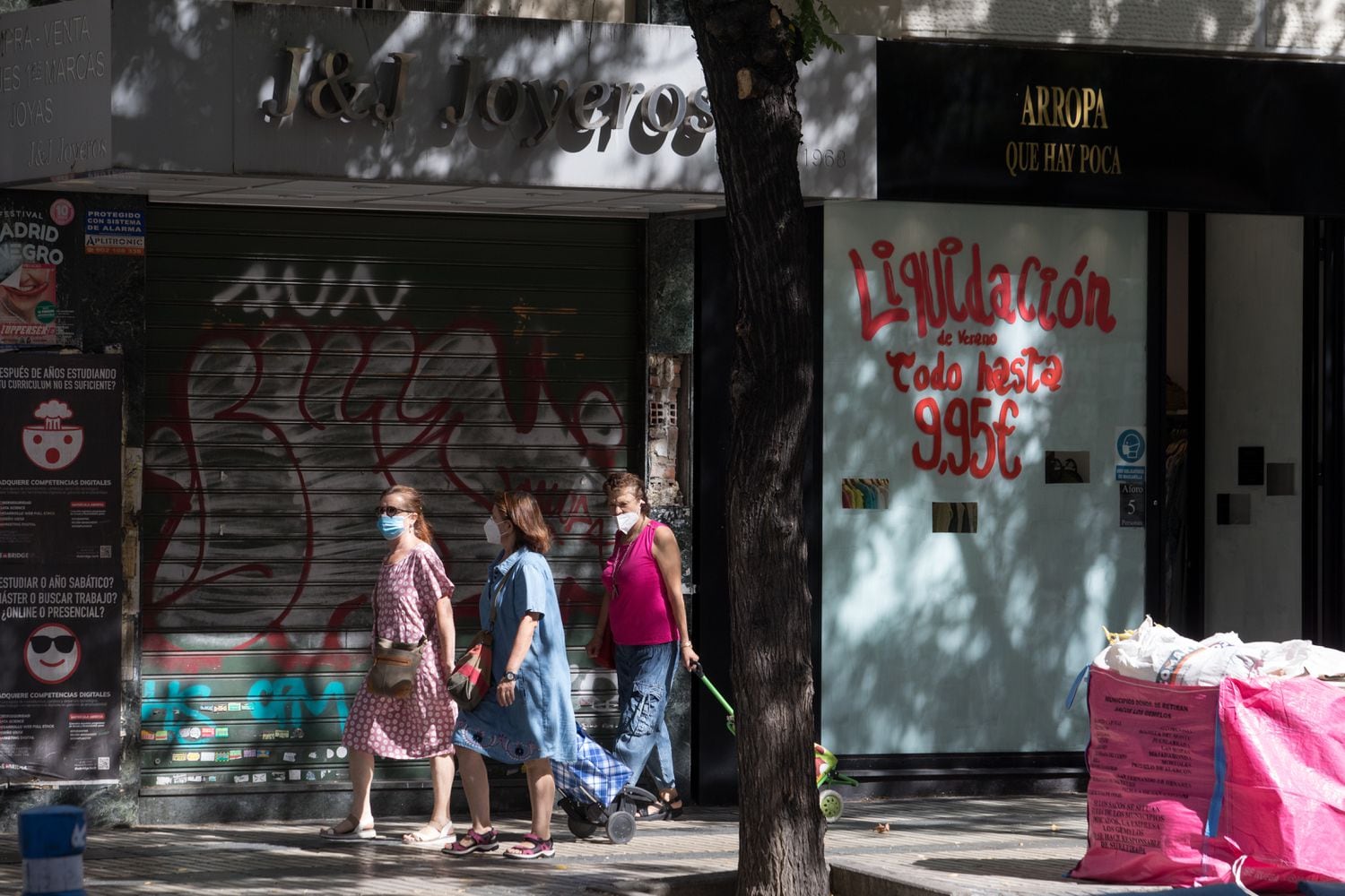 Tres personas pasan por delante de varios locales comerciales cerrados, este viernes en la calle de Alcalá, en Madrid.