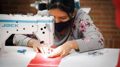 Una mujer aprende a operar una máquina en la sala de confección y costura de la 'Manzana del Cuidado' de Kennedy, en Bogotá.