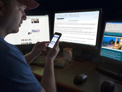 Un hombre revisa internet y sus redes sociales en un móvil y otras pantallas.