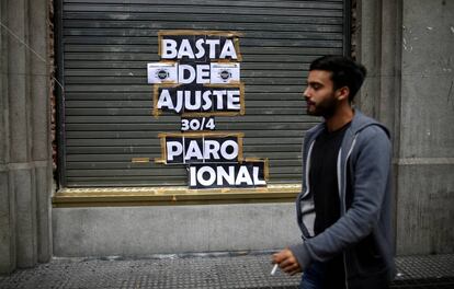 Un joven pasa frente a un local en Buenos Aires que tiene une pegatina donde se anunciaba la huelga general que se realizó el pasado 30 de abril.