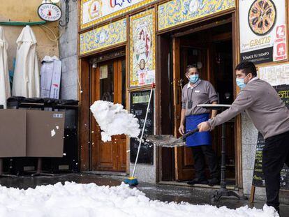 Personal de hostelería limpian de nieve las terrazas de los establecimientos en Madrid