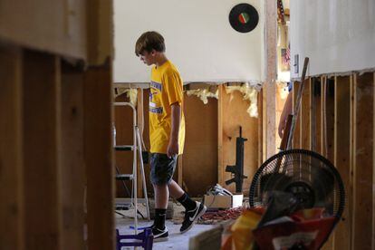 Un niño de trece años camina cerca de un rifle, en una de las casas afectadas por las inundaciones, en Prairieville, Luisiana (EE.UU).