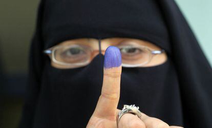 Una electora enseña su dedo entintado tras haber emitido su voto en un colegio electoral de Manial.
