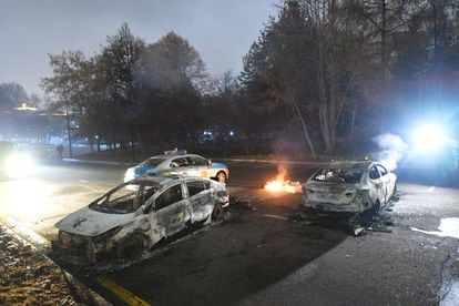 Varios coches de policía tras se quemados durante las protestas en Almaty, este miércoles.