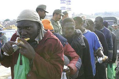Las Fuerzas Auxiliares suministran bocadillos a los subsaharianos detenidos durante la redada en el Gurugú