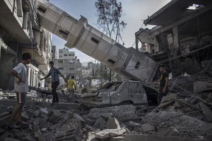 Varios palestinos pasan bajo el minarete de una mezquita derrumbado sobre la fachada de una vivienda en la ciudad de Gaza, el 30 de julio de 2014. La mezquita fue uno de los objetivos de los bombardeos del Ejército israelí la pasada noche.