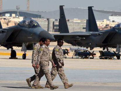 Tres oficiales saud&iacute;es caminan junto a unos cazas de reacci&oacute;n F-15, en enero en la base a&eacute;rea de Riad.