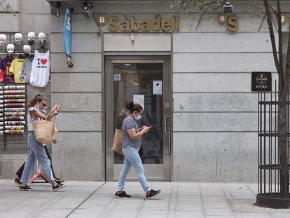 Dos mujeres pasan por una sucursal de banco Sabadell en Madrid.