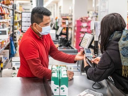 Un dependiente de un Dia en Madrid trabajando en la caja registradora del supermercado.