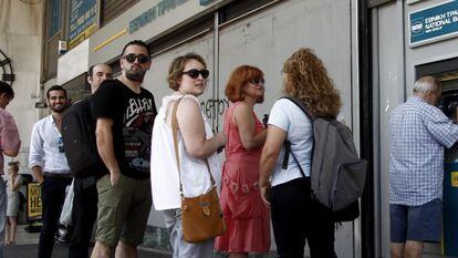 Varias personas hacen cola para retirar dinero de un cajero autom&aacute;tico en una sucursal del Banco Nacional de Grecia, en Atenas. 