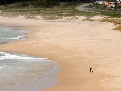 Una mujer de paseo con su perro por la playa de Doniños, en Ferrol (A Coruña).