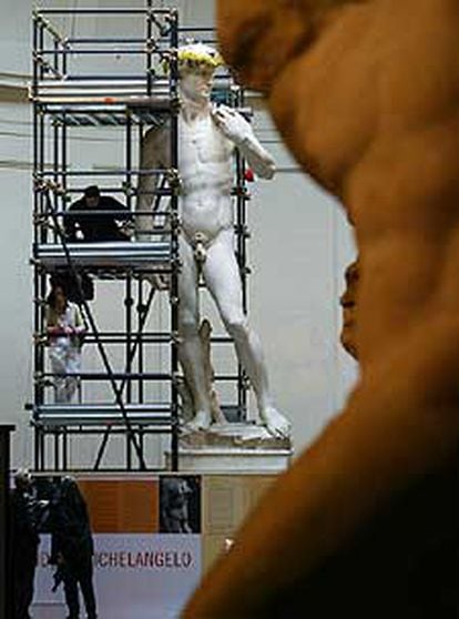 La jefa del equipo de restauradores coloca una guirnalda de mimosas a la estatua con motivo del Día de la Mujer.
