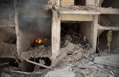 Un hombre se sienta en los escombros de un edificio destruido por los ataques aéreos de las fuerzas del Gobierno sirio, en Alepo.
