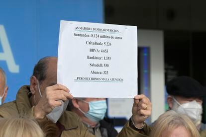 Un hombre sostiene un cartel con datos de los beneficios de la banca en una protesta contra la exclusión financiera, este lunes en A Coruña.
