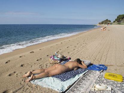 Una dona pren el sol a la platja de la Murtra a Sant Pol de Mar (Maresme).