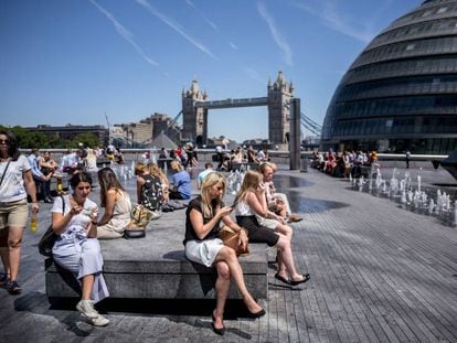 Turistas y ciudadano sen general se toman un descanso cerca de City Hall en el centro de Londres el 2 de julio de 2018