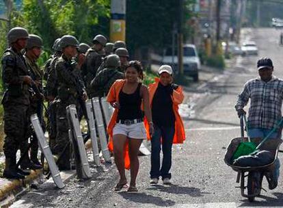 Tres trabajadores superan un control militar situado cerca de la residencia presidencial en Tegucigalpa.