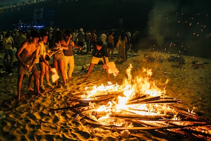Un grupo de adolescentes quema los exámenes y apuntes de la EBAU en una de las hogueras de la playa de Riazor, A Coruña.  