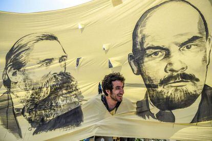 Un hombre saca la cabeza a través de un agujero entre las imágenes del filósofo y pensador comunista, Friedrich Engels (i) y el líder soviético y pensador comunista, Vladimir Ilitch Lenin, durante la marcha de los trabajadores en Estambul (Turquía).