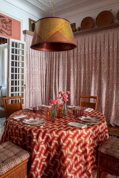 La mesa del comedor está vestida con un mantel diseñado por David Hicks para Cabana. La  lámpara colgante de cobre pintado es de Renzo Mongiardino; las sillas son de la firma Bonacina, y las cortinas, un diseño de Ashley Hicks.