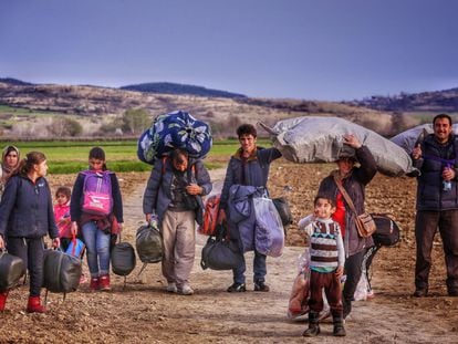 Una familia siria, que ha logrado escapar de una zona en conflicto, se encaminan hacia en campo fronterizo de Idomeni (Grecia).