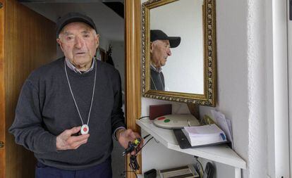 Un anciano muestra el botón de teleasistencia y la conexión de su casa, estropeados.