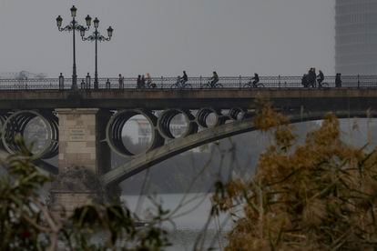 Un grupo de personas en bicicleta por el carril bici del puente de Triana, este lunes en Sevilla.