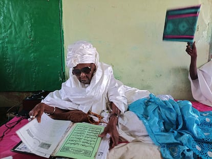 Sokhna Saibata consulta versículos coránicos mientras es abanicada por un discípulo.