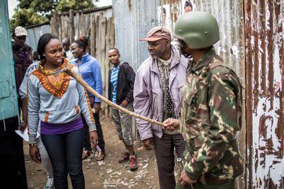 La comisión electoral reconoció "algunos problemas en algunos centros de votación" relacionados con el sistema biométrico de identificación de los electores, que, no obstante, parecía funcionar mejor que en 2013. En la imagen, un policía keniano con un palo dirige a los votantes, en un centro electoral de Nairobi (Kenia).