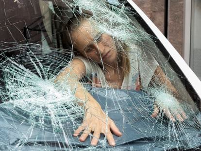Una mujer protege el interior de un vehículo dañado por el granizo caído en La Bisbal de l'Empordà.