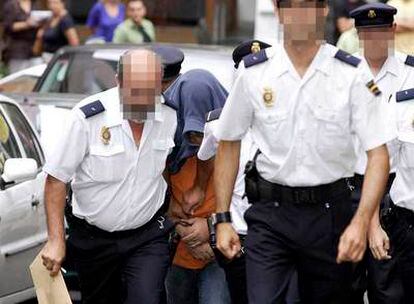 Un grupo de policías conduce al juzgado al ex agente del CNI, esposado y con la cabeza cubierta.