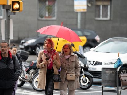 Varias personas con paraguas pasean por Barcelona este viernes.