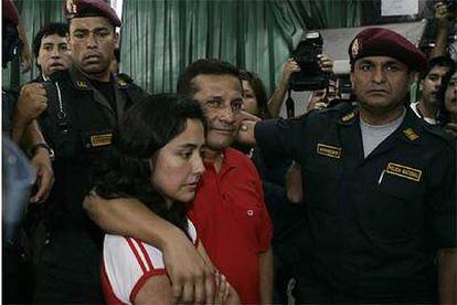 El candidato Ollanta Humala y su esposa, protegidos por policías, aguardan para poder abandonar el colegio electoral, rodeado por manifestantes.