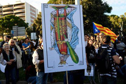 Un manifestant sosté una carta gegant que representa el rei de bastos, cap per avall, durant la protesta independentista contra la visita de la família reial a Barcelona.