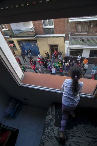 Una niña mira desde la ventana a un grupo de manifestantes que protesta contra el desahucio de su familia