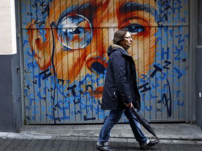 Un hombre pasea por una calle del Barrio de las Letras frente a un mural de Zaida Escobar.