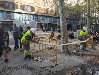 Dos operarios vallan una zona deteriorada tras los disturbios de los últimos días en Barcelona.