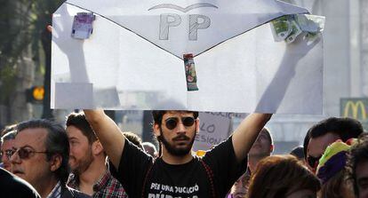 Un joven levanta un sobre con las siglas del PP en la manifestación contra la corrupción de este sábado.