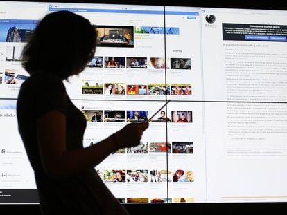 Una usuaria consulta una tableta frente a una pantalla con la página de Youtube.