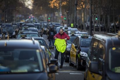 Un taxista se dispone a colocarse un chaleco amarillo durante la protesta en la Gran Vía barcelonesa.