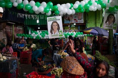 Vendedoras de La Terminal trabajan delante de un cartel de Sandra Torres este 18 de agosto en Ciudad de Guatemala.